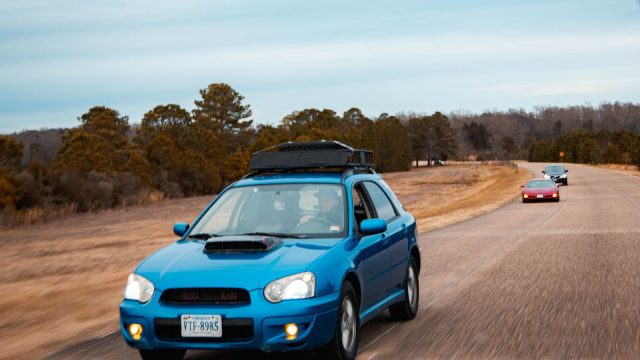 Car with roof rack driving on an open road, ready for a longer trip